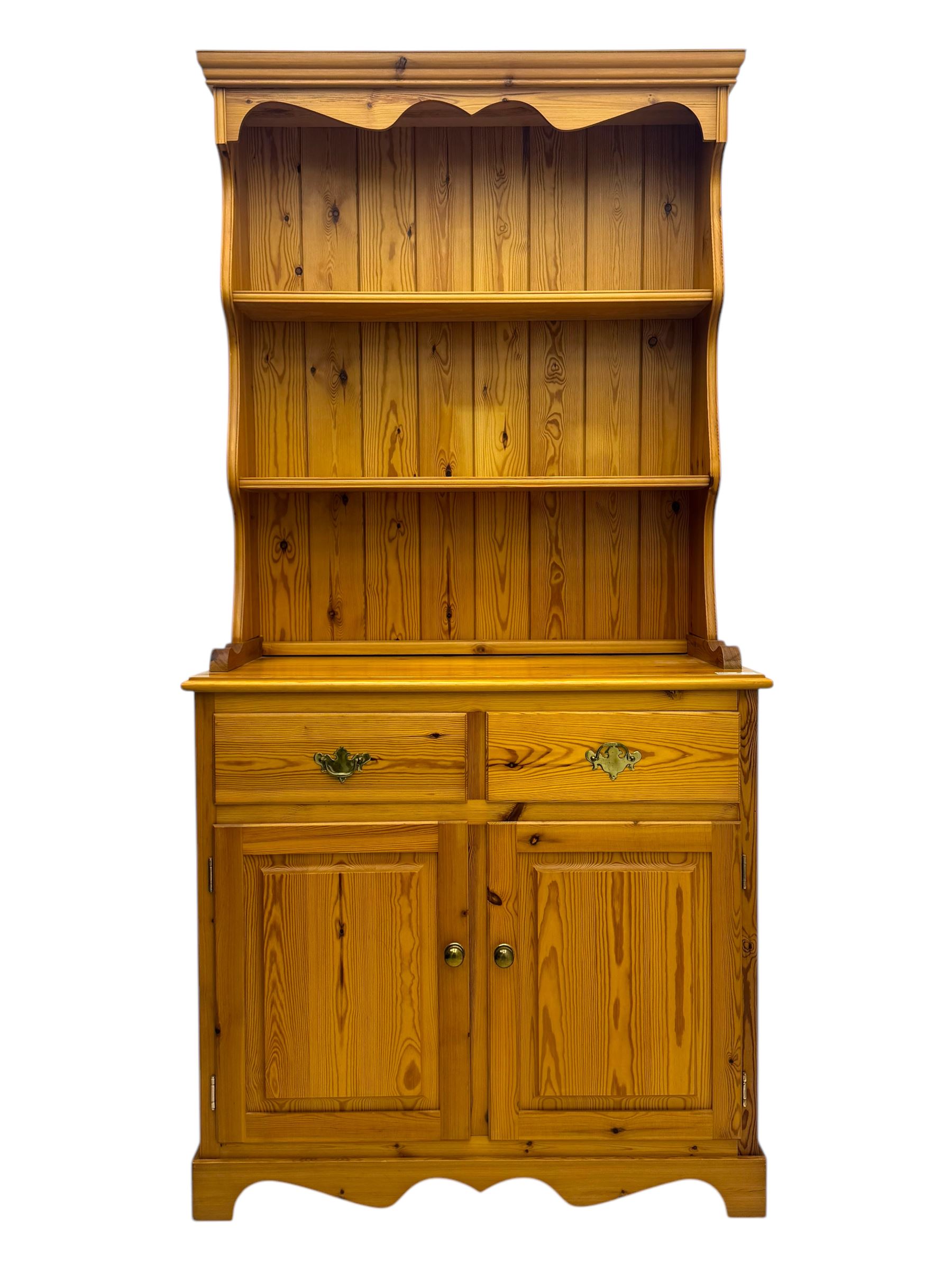 Victorian design pine dresser, projecting moulded cornice over scalloped frieze and two open shelves, base fitted with two drawers over double cupboard, on shaped plinth base