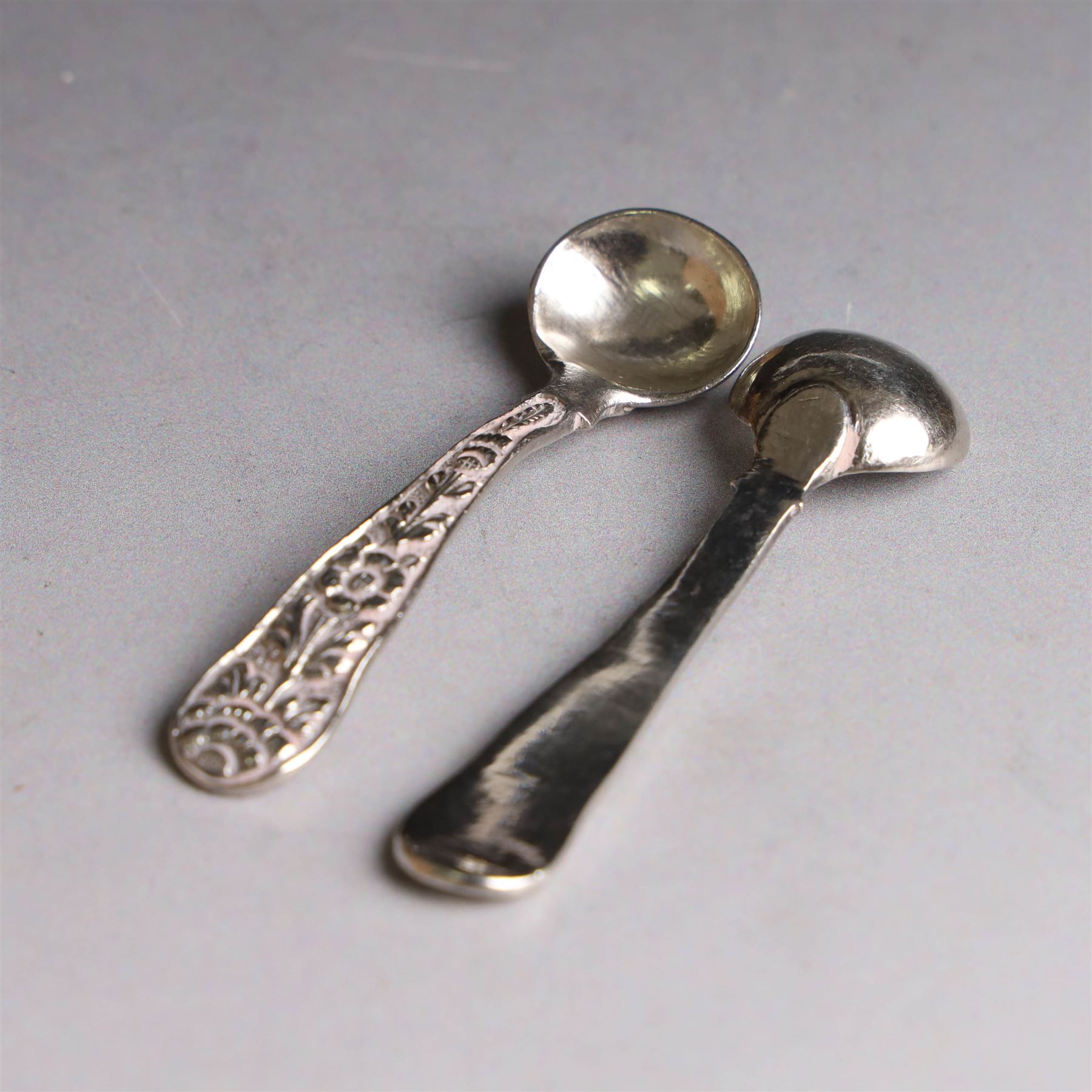 Pair of Middle Eastern silver cruets, of spherical form with pierced tops, embossed with figures, elephants and village scenes, unmarked, together with a pair of silver condiment spoons embossed with floral decoration 