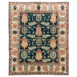 Persian emerald green ground rug, the field decorated with large stylised plant motifs, ivory ground border with repeating leaf motifs, the guards decorated with trailing branch and flowerhead motifs