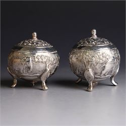 Pair of Middle Eastern silver cruets, of spherical form with pierced tops, embossed with figures, elephants and village scenes, unmarked, together with a pair of silver condiment spoons embossed with floral decoration 