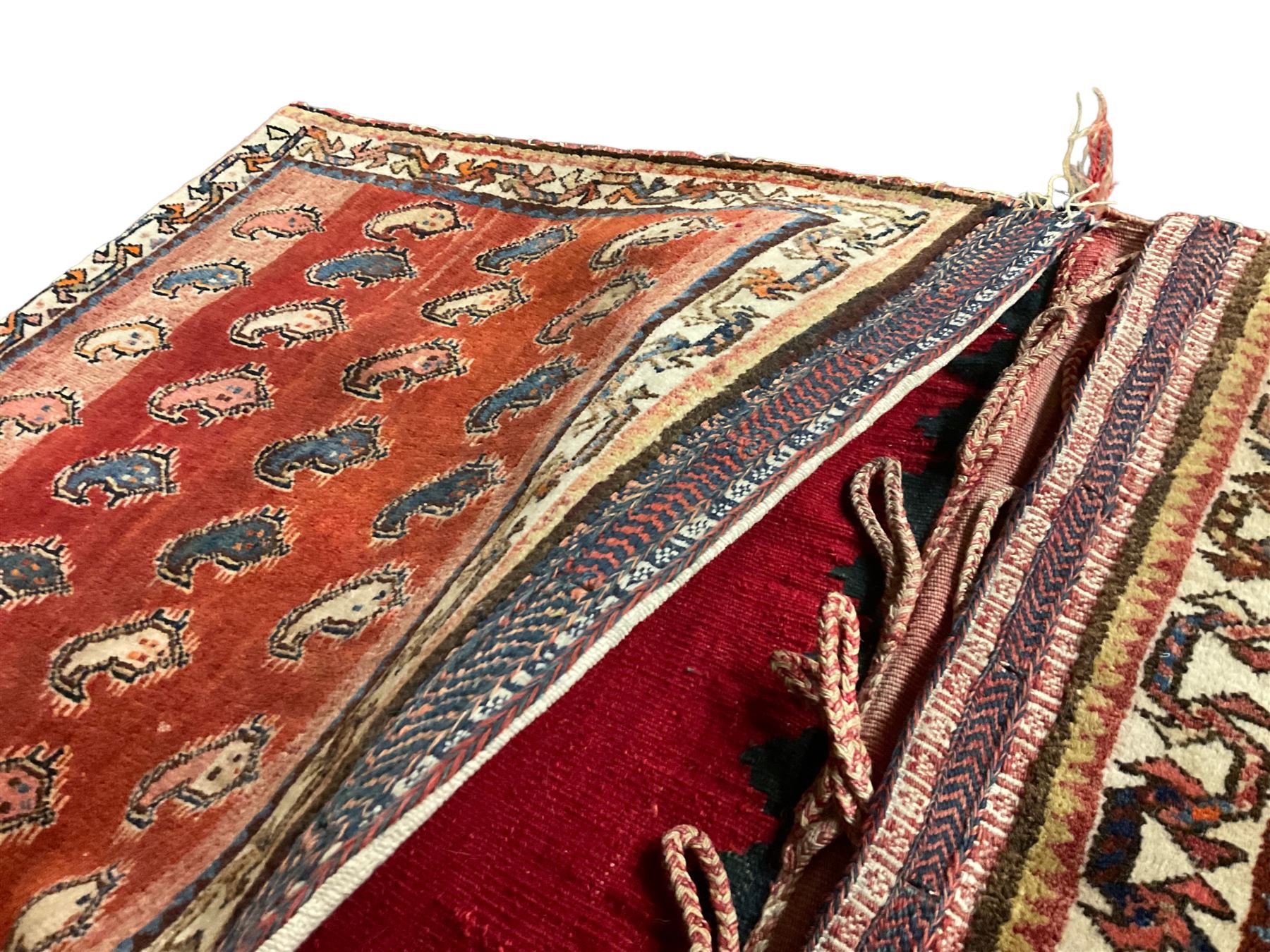 Antique Persian red ground saddle bag, decorated with all-over Boteh motifs, geometric patterned border (127cm x 68cm); Persian indigo ground saddle bag, decorated with two geometric ivory lozenges (113cm x 62cm); Persian red ground saddle bag decorated with lozenges and multi-band border (110cm x 65cm) 