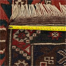 Caucasian Kazak rug, red field with three bold geometric medallions in dark blue, cream and brown, scattered tribal motifs, broad indigo border decorated with stylised hooked forms and multiple narrow patterned borders