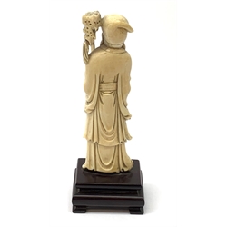 A Chinese carved ivory okimono, modelled as a sage holding a staff, raised upon a wooden base, overall H15.5cm. 