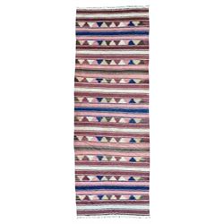 Kilim muted pink ground runner, decorated with rows of horizontal bands in muted tones, alternating with geometric triangular patterns along each band, fringed ends