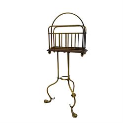 Edwardian oak and brass revolving magazine stand, arched frame with slatted slides and oak base, mounted on a brass column supported by three stylized scrolling legs terminating in pad feet