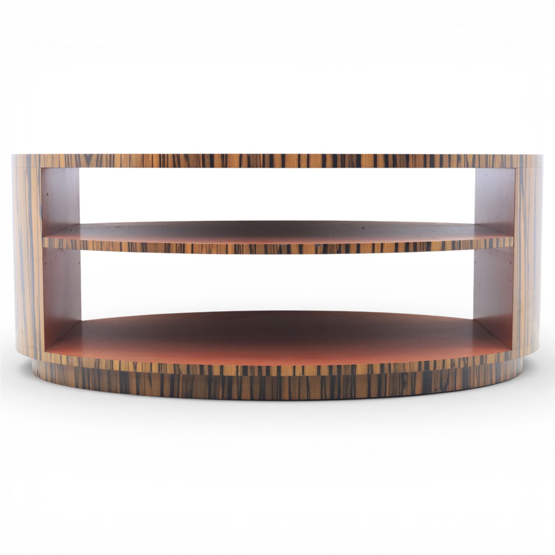 Toby Winteringham - Mid 20th century zebra wood coffee table, oval top with book matched striped veneers over two open tiers painted red, the curved end supports and continuous plinth base veneered to match, recessed plinth base 