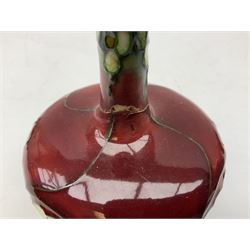 Three Minton Secessionist vases, with tube-lined stylised flower decoration, two upon a red ground and third upon a purple ground, all with printed mark to base 'Minton Ltd, No. 33', H13cm