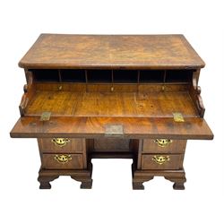 Early 18th century Queen Anne figured walnut kneehole desk with secretaire drawer, moulded and book matched top with walnut band, the top drawer with fall front enclosing small drawers and pigeon holes, fitted with nine drawers and central recessed cupboard, on ogee bracket feet