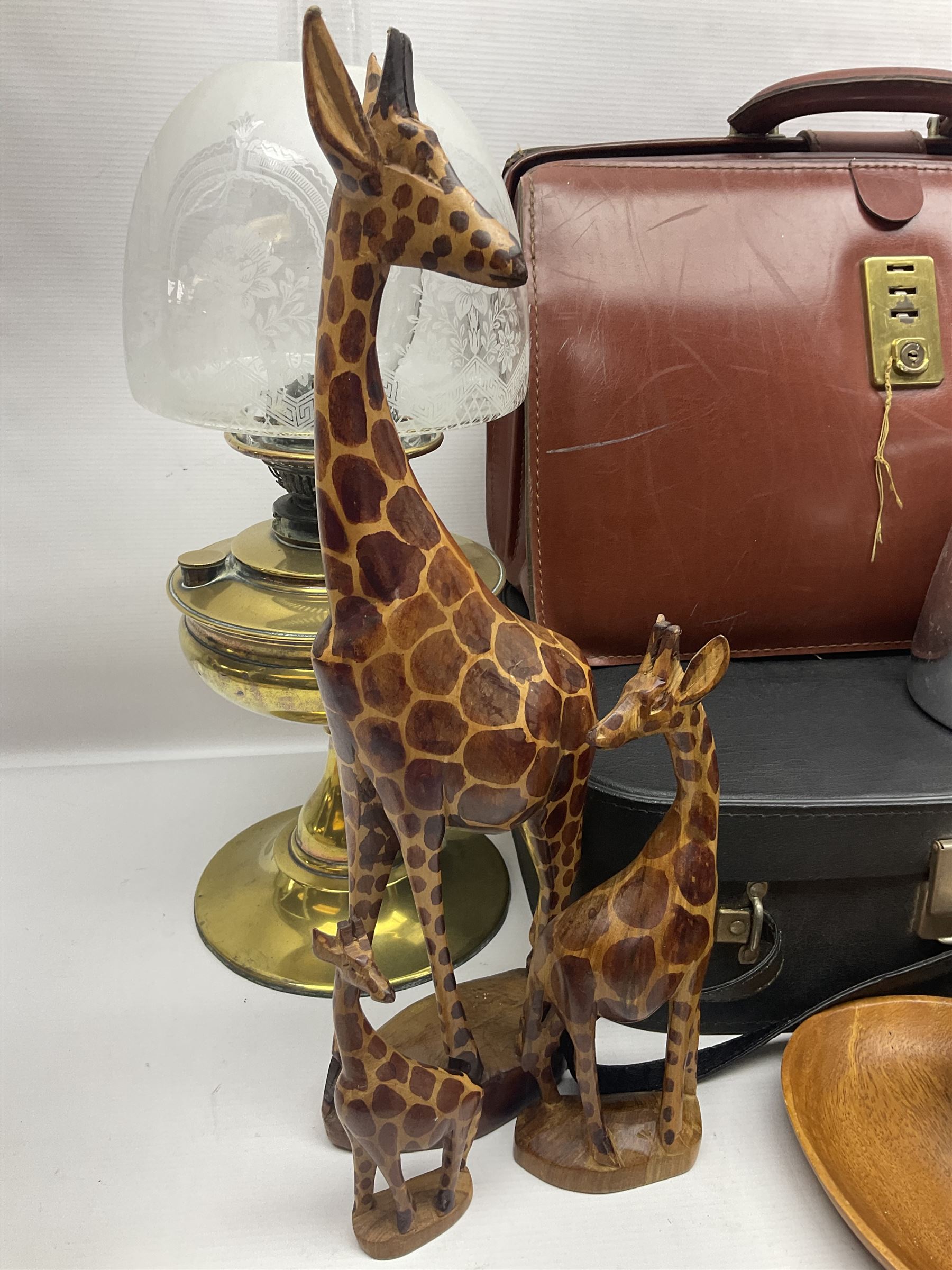 Brass oil lamp, with etched floral glass shade, leather Gladstone style doctors bag, leather satchel and vintage vanity case, three graduating wooden giraffes and other wood and metal ware, lamp H54cm
