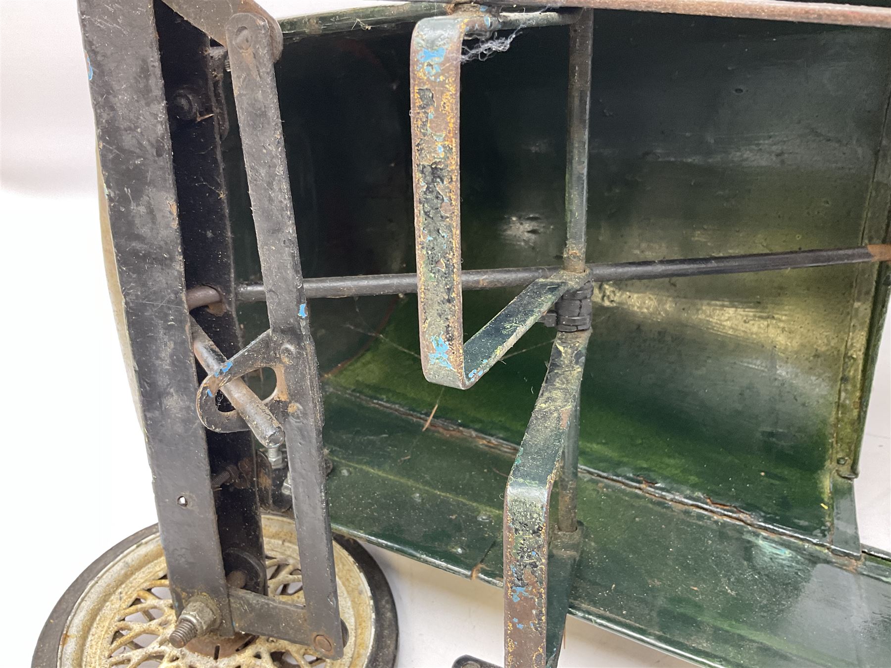 Mid 20th century pressed steel pedal car, the body painted in dark green fitted with pretend radiator to the bonnet, with spoked wheels and rubber tyres, the interior with pedals and steering wheel, L70cm