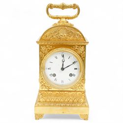 Fine Swiss ormolu 8-day early 19th century Pendule d'Officer style clock c1820,  circular double train ting-tang movement striking the quarters on a graduated pair of bells and sounding the hour on one, going train with a vertical platform lever escapement and over sprung balance, rack striking, with visible hour and quarter strike work to the backplate, movement unsigned, convex enamel dial with Roman numerals and steel moon hands behind a glazed gilt bezel, case with a scroll cast handle to the arched top with applied rococo decoration to the tympanum, both sides of the case adorned with a military trophy of arms motif and deep frieze with foliate arcading beneath, on a rectangular plinth with decorative scroll engraved bracket feet. With Key.   