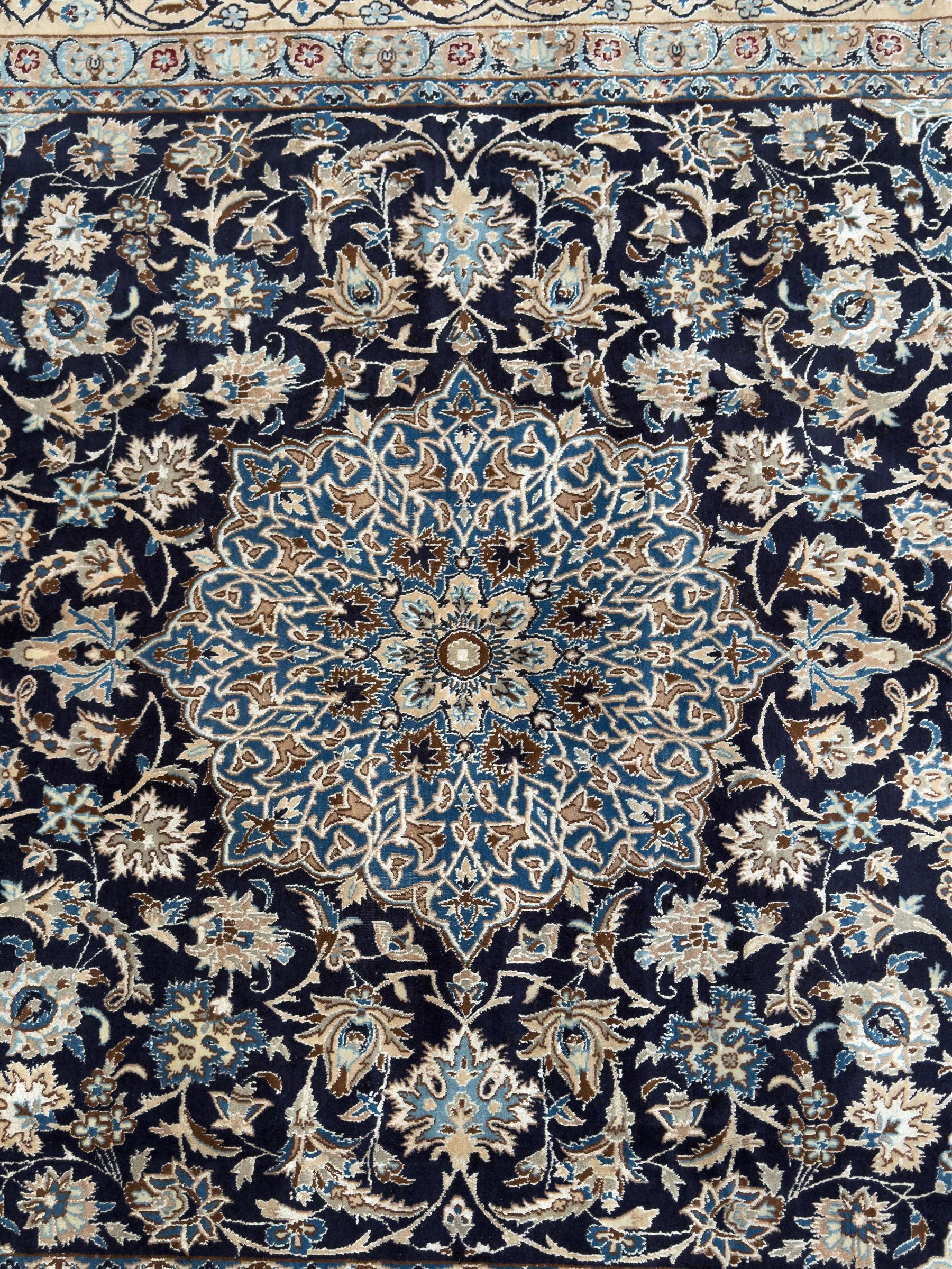 Central Persian Nain carpet, the deep blue field with finely drawn scrolling palmettes and flowering vines around a central ivory and sky blue rosette medallion, enclosed by an ivory border of interlaced floral arabesques and lotus forms between multiple guard stripes, from the region of Nain