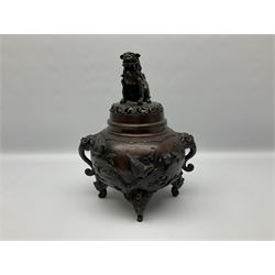 Japanese bronzed koro, the body of globular form with twin cast zoomorphic mask handles, decorated in relief with birds upon blossoming branches, against a ground incised with rushes and peonies, the flat toped domed cover with pierced band and surmounted by a cast figure of a Foo dog, the whole upon three zoomorphic mask feet, with impressed character type mark beneath, H35.5cm