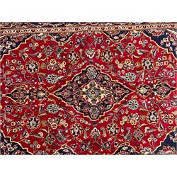 Persian crimson ground rug, the central indigo pole medallion within a field decorated with palmettes and floral patterns with contrasting spandrels, guarded border with repeating rinceaux patterns