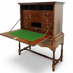 Early 18th-century George I walnut bureau cabinet on later stand, moulded rectangular cornice above fall front, inlaid oval burr walnut panel opening to reveal a fitted interior of drawers, pigeon holes, and a central cupboard door, with baize-lined writing surface above a long drawer over a shaped apron and turned legs joined by a turned stretcher, lacks key, later brass strut supports
