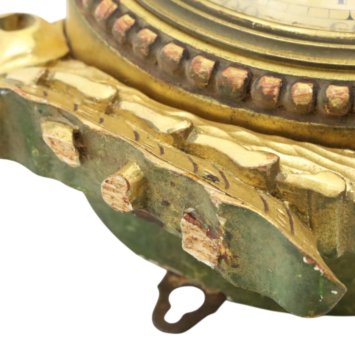 20th century Continental giltwood wall clock, circular dial with Arabic numerals and pierced gilt hands, within a carved case surmounted by a scrolling crest and flanked by stylised dolphins, above a shaped shelf with tassel pendants and a foliate terminal, pendulum missing
