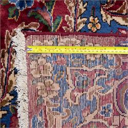 Large Central Persian Kirman hand-knotted carpet, raspberry red field, with central shaped medallion surrounded by an intricate arrangement of scrolling vines and floral sprays, within conforming spandrels and a pale blue border decorated with floral motifs, enclosed by guard stripes, with cotton fringe ends 