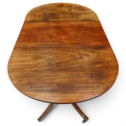 George III mahogany twin pedestal extending dining table, the twin D-ends with additional leaf, raised on twin turned pedestals terminating to four splayed supports with brass cups and castors