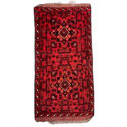 Small Persian magenta ground rug, central Mirab with flanking columns enclosing stylised urn motif with trailing foliage, the triple band border with plant motifs (86cm x 46cm); Persian red ground rug, two central floral medallions with extending flower heads, floral decorated border (106cm x 53cm) (2)