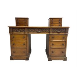 Late 19th century heavily carved oak twin pedestal desk, rectangular top with two raised trinket or correspondence structures each with three drawers, rectangular top over three frieze drawers carved with acorn and oak leaf decoration, each pedestal with three drawers with acorn husk shaped handles