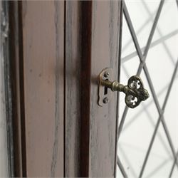 Mid 20th century oak display cabinet, the moulded rectangular cornice above a pair of leaded glazed doors with diamond lattice glazing, enclosing adjustable shelving, the lower section fitted with four short drawers with brass ring handles, flanked by chamfered uprights with carved leaf detail