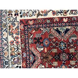 Pair of rugs one Persian hamadan rug central stepped medallion enclosing geometric motifs in ivory and brown, framed by a cream border with scrolling palmettes and fringed ends (H 156cm W 105cm), one Pakistani Bokhara rug rust red ground with repeated Tekke gul motifs within rosette and lozenged borders, fringed ends (H 98cm, W 65cm)