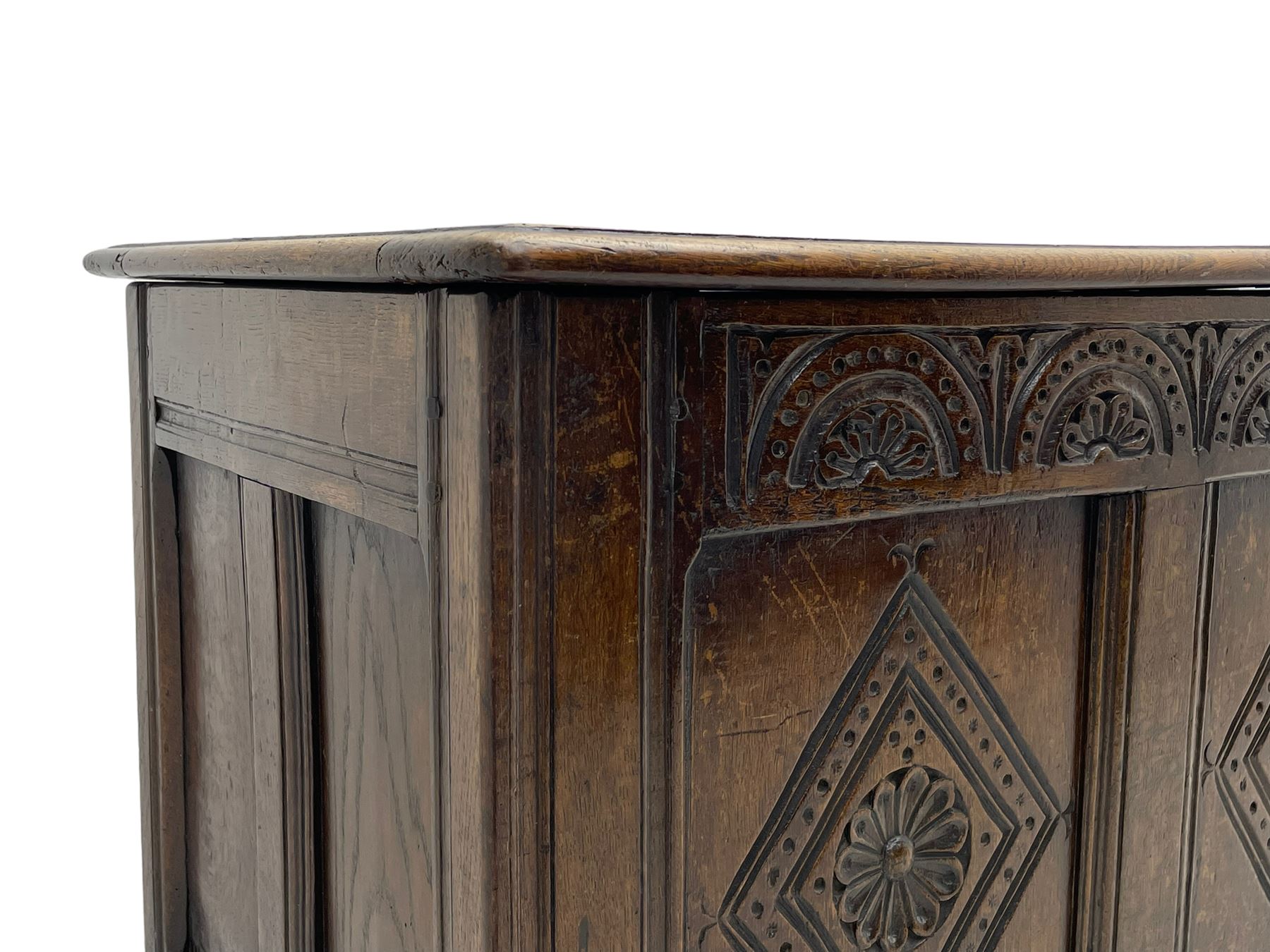 18th century oak coffer or chest, rectangular triple panelled hinged top with moulded edge enclosing main compartment and candle box, the frieze carved with repeating concentric lunettes and foliate patterns, the front fielded panels decorated with lozenges containing central flower heads, on stile supports