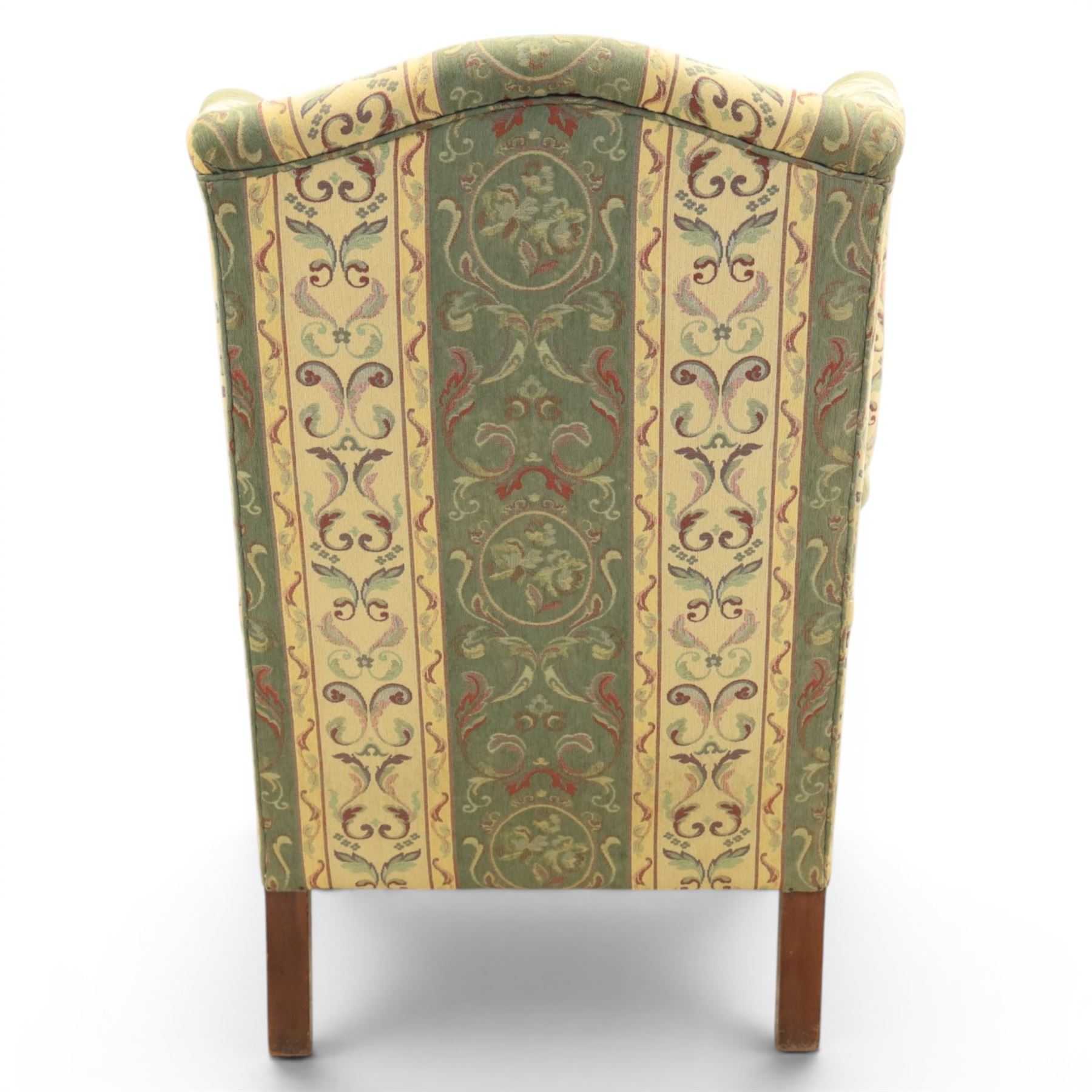 Queen Anne style wingback armchair, upholstered in green and cream foliate fabric, shaped arms on ball and claw feet