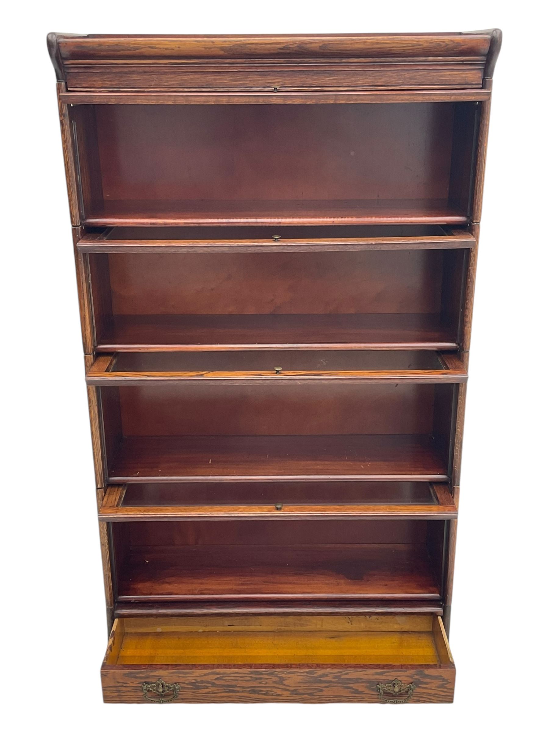 Early 20th century oak stacking library bookcase, four sections enclosed by hinged and sliding glazed doors, fitted with single drawer 