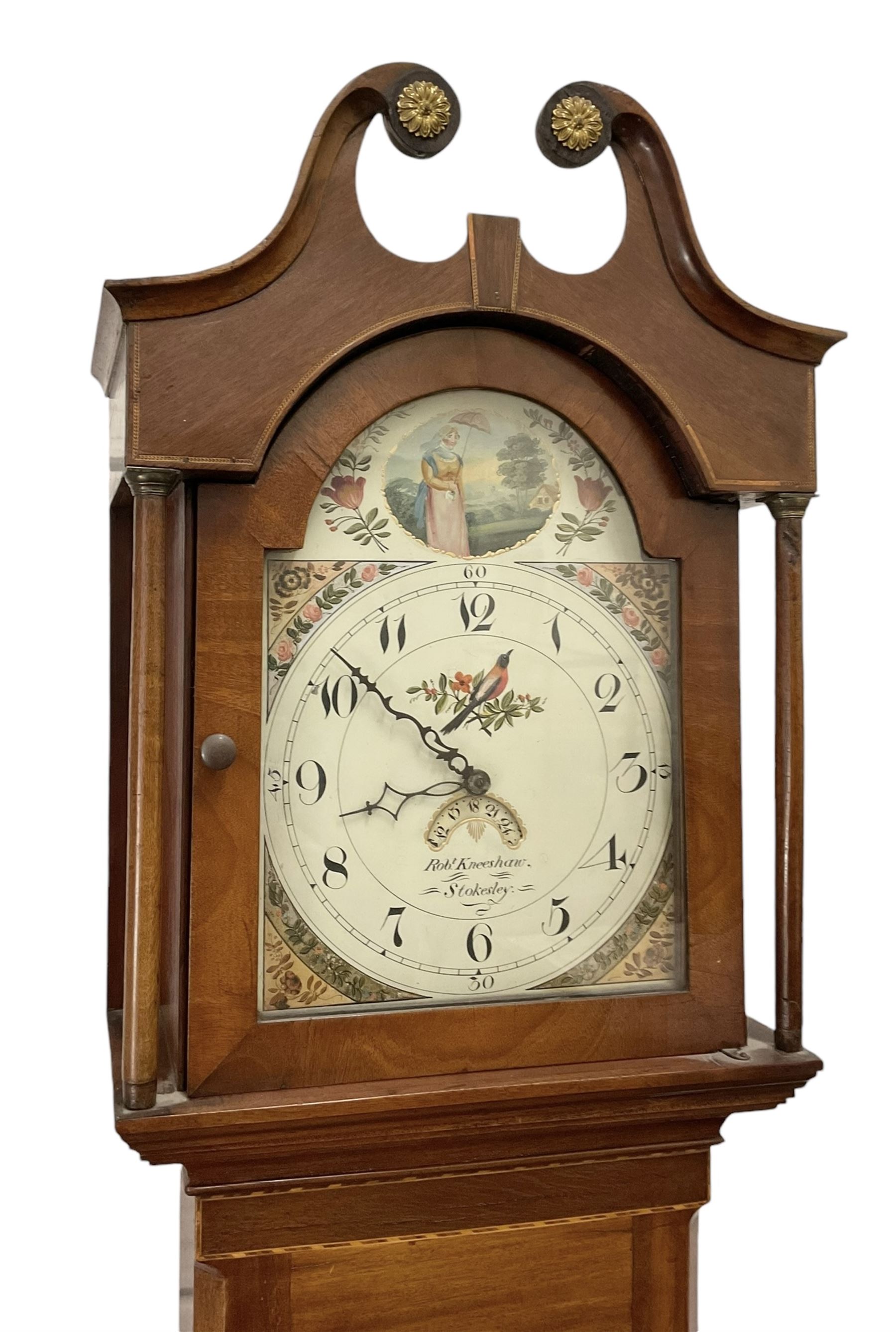 Robert Kneeshaw of Stokesley - 19th century 30 hour mahogany cased longcase clock c1820. with a swans necked pediment and brass paterie, break arch hood door with plain pilasters, inlaid trunk with canted corners, inlay and a wavy topped door, on a rectangular plinth with a shaped base, painted dial with floral spandrels and a depiction of a lady walking in the countryside, with Arabic numerals, non-matching steel hands, calendar aperture and an image of a bird of paradise to the centre, chain driven countwheel striking movement, with weight and pendulum.  