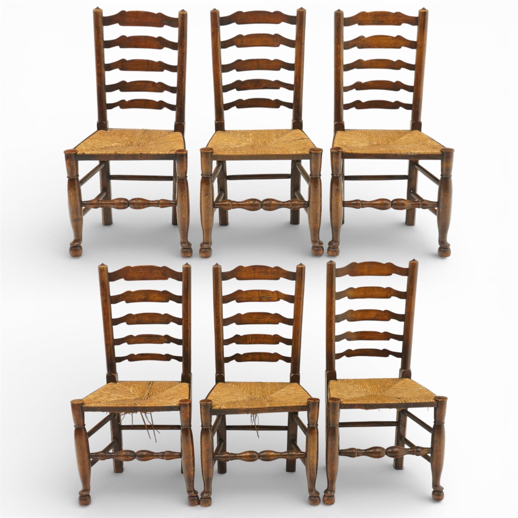 Early 19th century set of six country ladder back chairs, each with five shaped horizontal slats, woven rush seats within square frames, standing on turned forelegs united by peripheral stretchers with turned front rail
