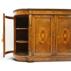 Large fine Victorian figured and burr walnut credenza, the breakfront D-shaped top with moulded edge, over an ornate frieze with inlaid Aesthetic Movement scrolling and geometric ornament, applied with gilt-metal ribbon-twist moulding and mounts, the central panelled doors profusely inlaid with scrolling foliate motifs and stringing, flanked by gilt-metal cartouche and scrolling acanthus corbel mounts, with flanking glazed bow-front side doors, on skirted base with further gilt metal foliate mounts