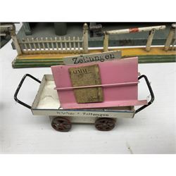 '0' gauge - Bing tin-plate two-storey double sided station with open walk-through to one end, rail side canopy, hinged doors and removable roof giving access to clock illumination L35cm; Bing hand-cranked turntable and open wagon; Marklin tin-plate level crossing barrier and Newspaper vendor's tin-plate four-wheel hand cart (5)