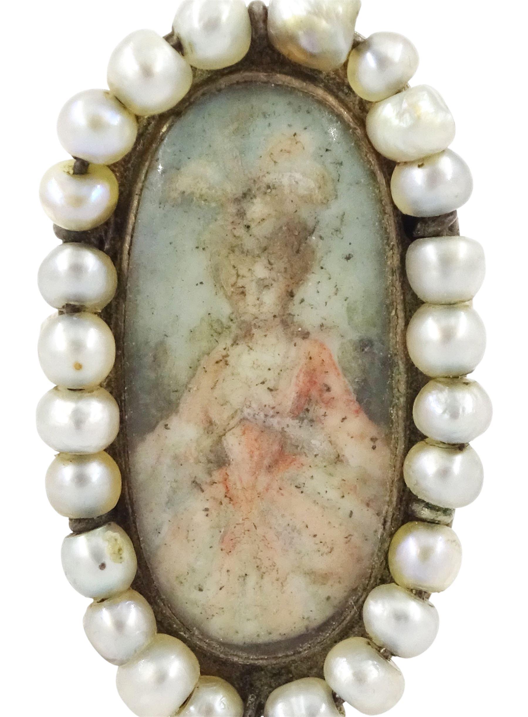 19th century portrait ring, set with an oval miniature of a woman wearing a pink dress on ivory, under a glazed panel, with threaded pearl surround and engraved shoulders. This lot has been registered for sale under Section 10 of the APHA Ivory Act