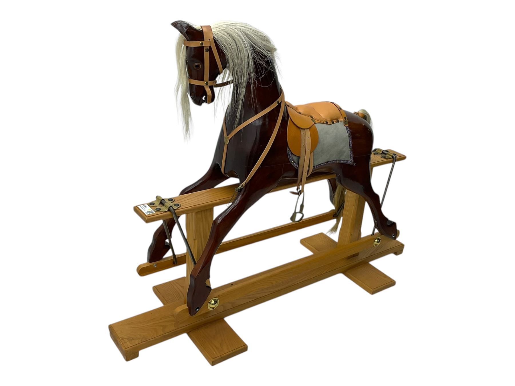 Contemporary carved wooden rocking horse, with leather saddle and bridle, horsehair mane and tail, raised on a pine stand with swing iron supports