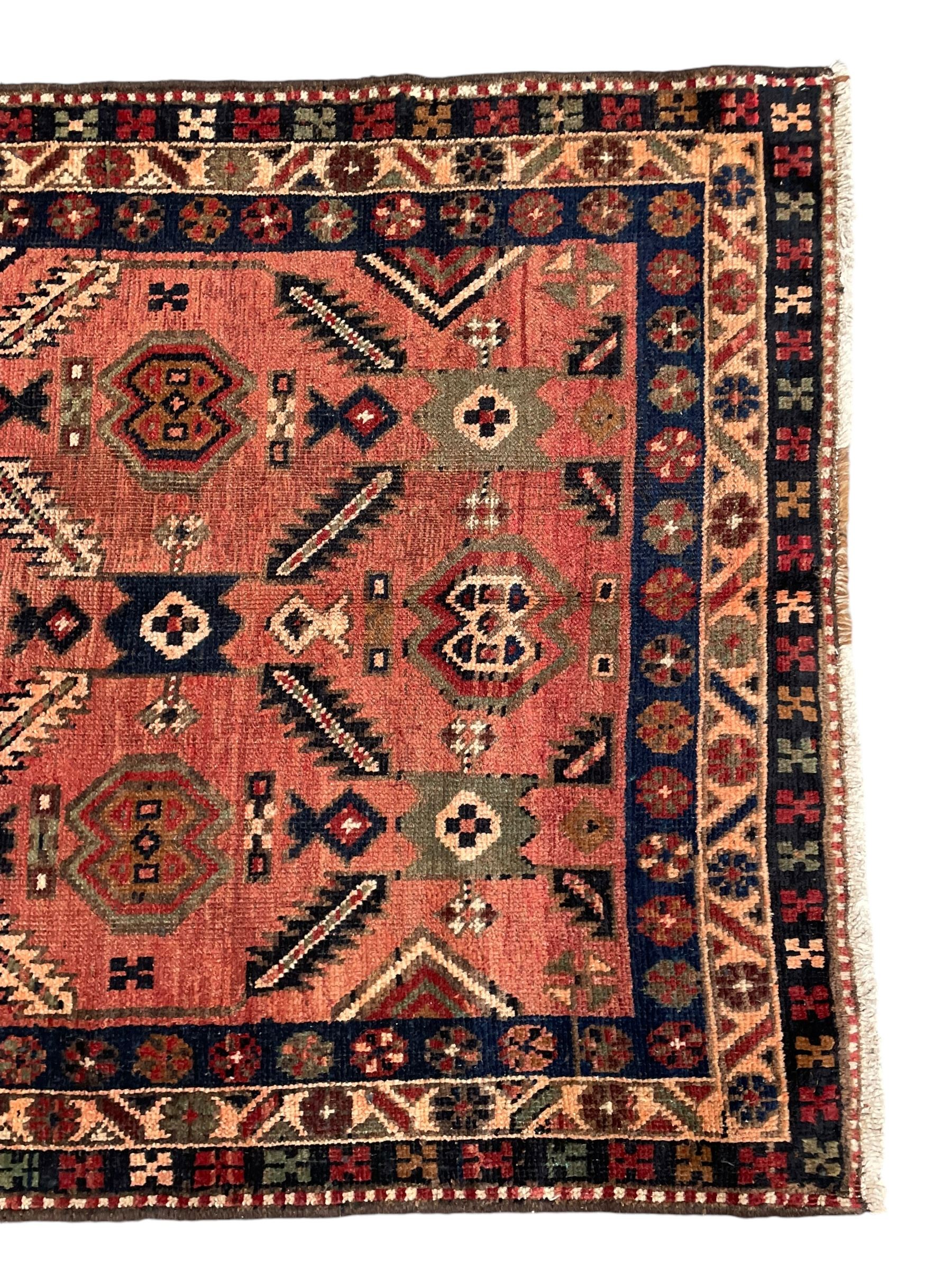 Near pair of Persian Azerbaijan red ground runners, each rug decorated with Nazarlik and stylised leaf motifs, enclosed with three band border decorated with flower heads and geometric motifs 

406cm x 99cm 
409cm x 102cm
