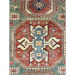 Kazakh rug, pale green ground field with three part medallion, three band border decorated with stylised plant motifs