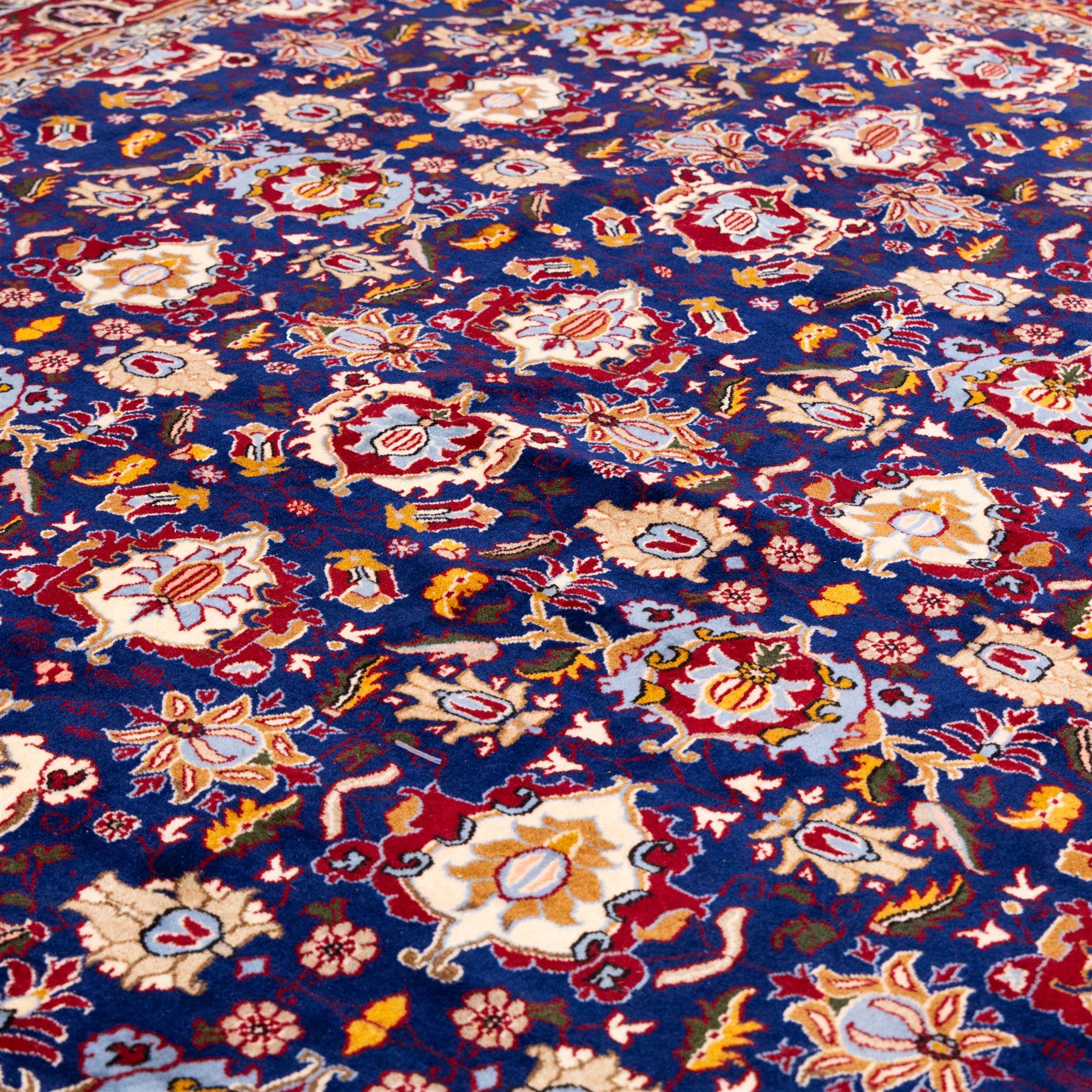 North Central Persian Veramin hand-knotted rug, deep indigo field decorated with an all-over lattice of stylized floral and palmette motifs issuing from an angular vine ornament, enclosed by a broad madder-red border of palmettes and scrolling vine devices between multiple guard stripes, with cotton fringe ends 