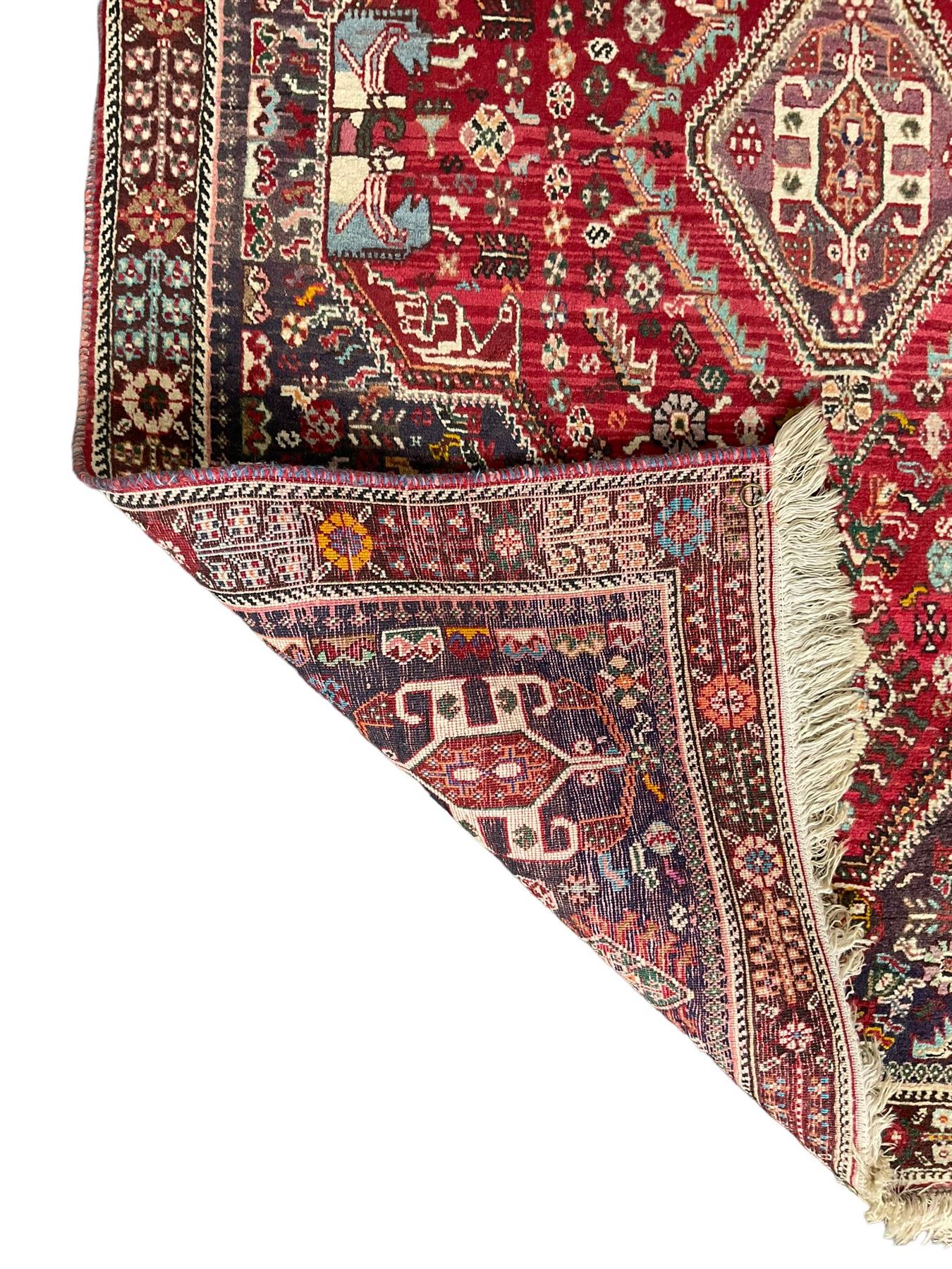 Persian Heriz crimson ground rug, field with large central lozenge surrounded by stylised plant motifs in a mauve background, guarded border with repeating foliage