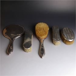 Five silver mounted dressing table items, including 1920s mirror and hairbrush set, with engraved initial to reverse, pair of clothes brushes with engraved initials and engine turned decoration and an oval clothes brush, all hallmarked 