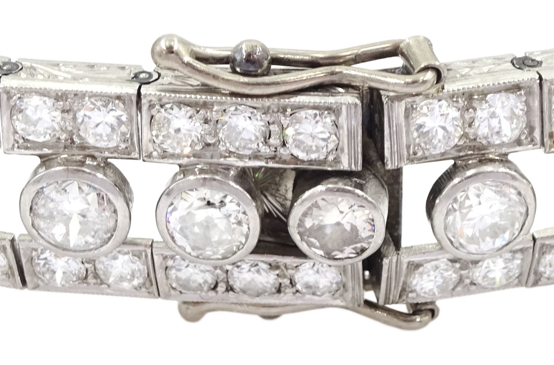 Continental Art Deco platinum old cut diamond openwork bracelet, circa 1920's, twenty-two bezel set graduating diamonds of approx 9.45 carat, the principal diamond approx 0.90, with a row milgrain set diamonds either side, the clasp set with a single diamond, the bracelet sides and clasp with engraved foliate decoration, total diamond weight approx 20.60 carat