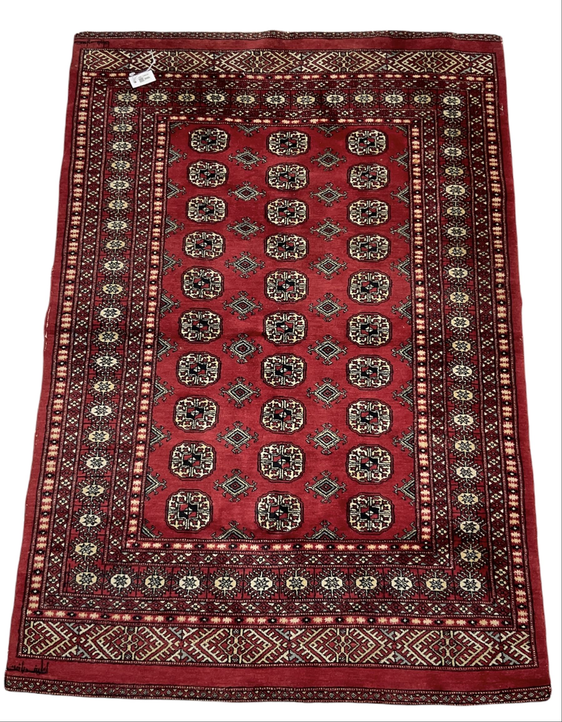 Turkmen Tekke Bokhara rug, red ground and decorated with Gul motifs, repeating multi-band border, signed on corners 