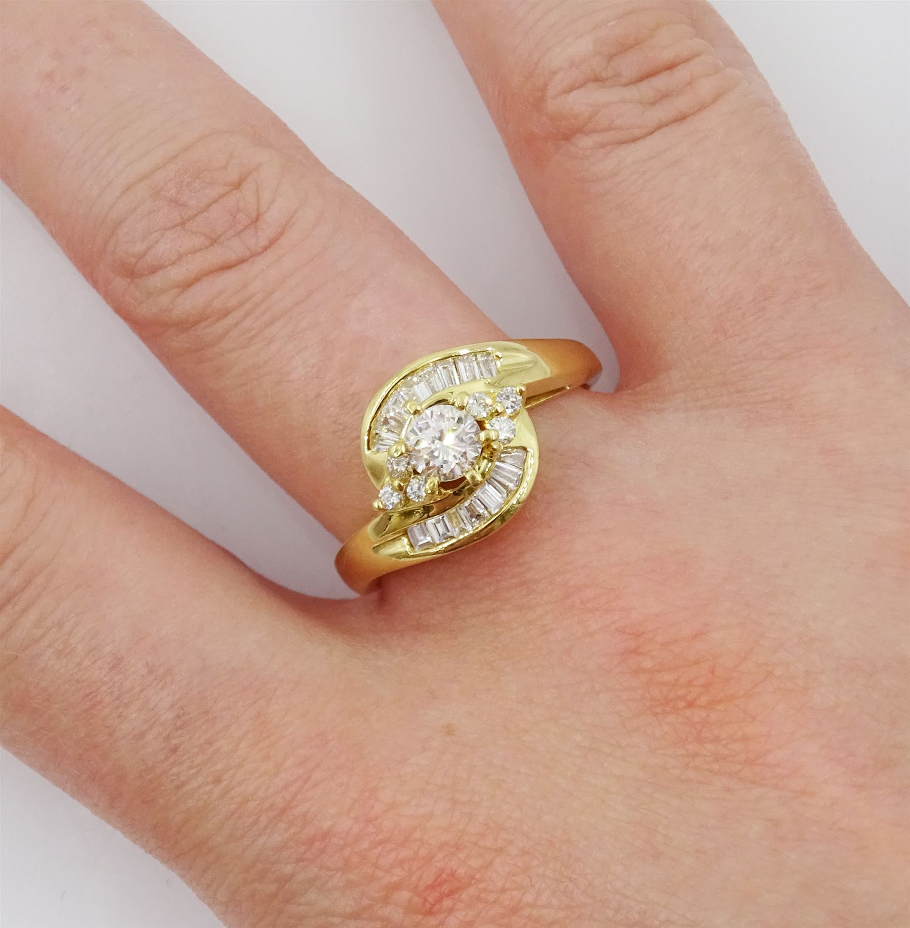 18ct gold diamond crossover ring, the central round brilliant cut diamond of approx 0.45 carat, with round brilliant and tapered baguette cut diamond surround, total diamond weight approx 1.00 carat
