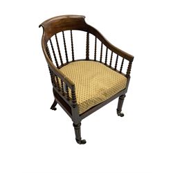 William IV rosewood tub armchair, the arched bow cresting rail over graduated bobbin turned spindles, cane seat with loose cushion, terminating in brass cups and castors.
