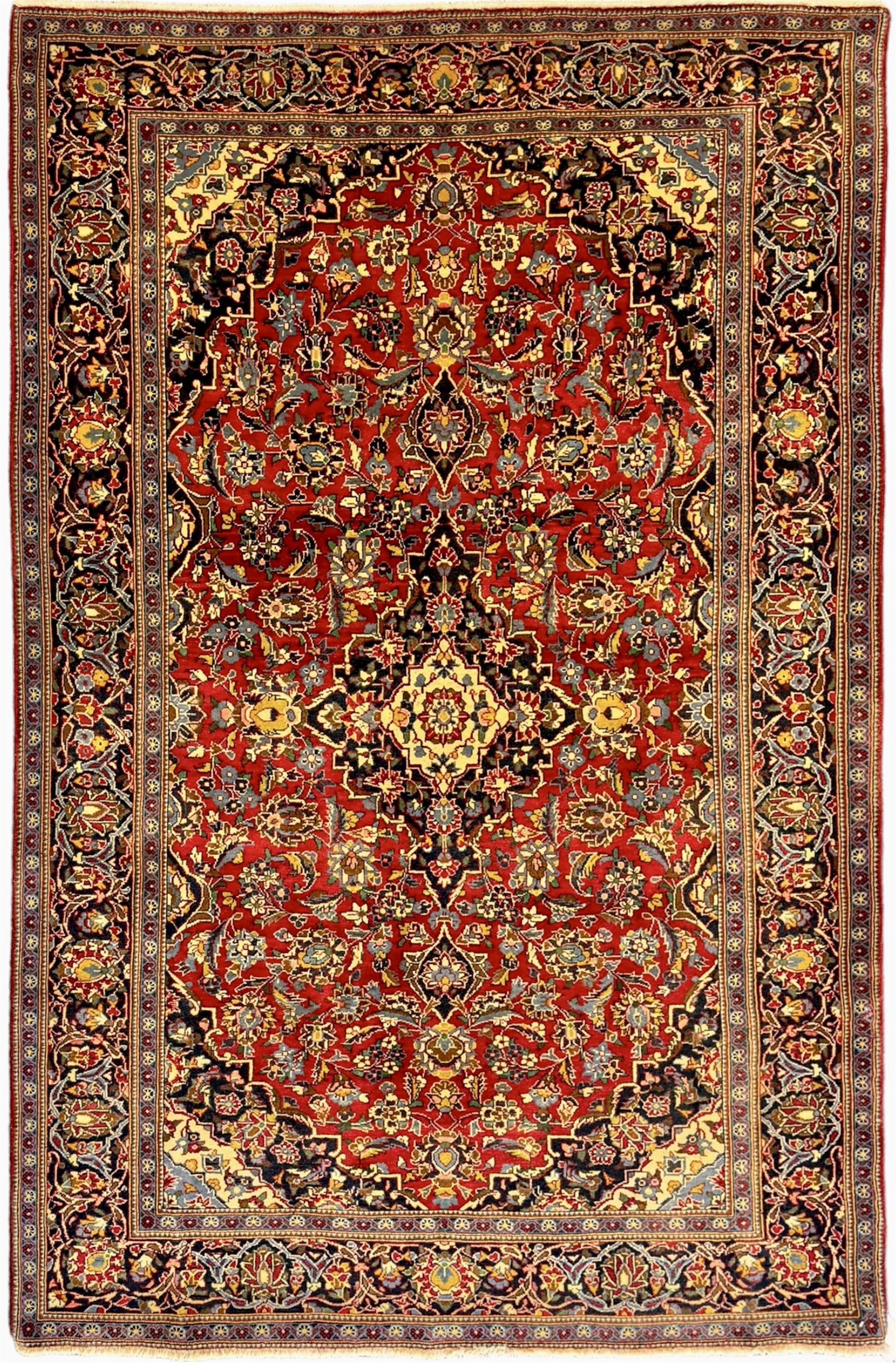 Central Persian Kashan crimson ground rug, central indigo pole medallion surrounded by sparsely placed bouquets interconnected with foliate branches, the guarded border with repeating palmette and Boteh motifs with interwoven scrolling patterns, framed by guard stripes