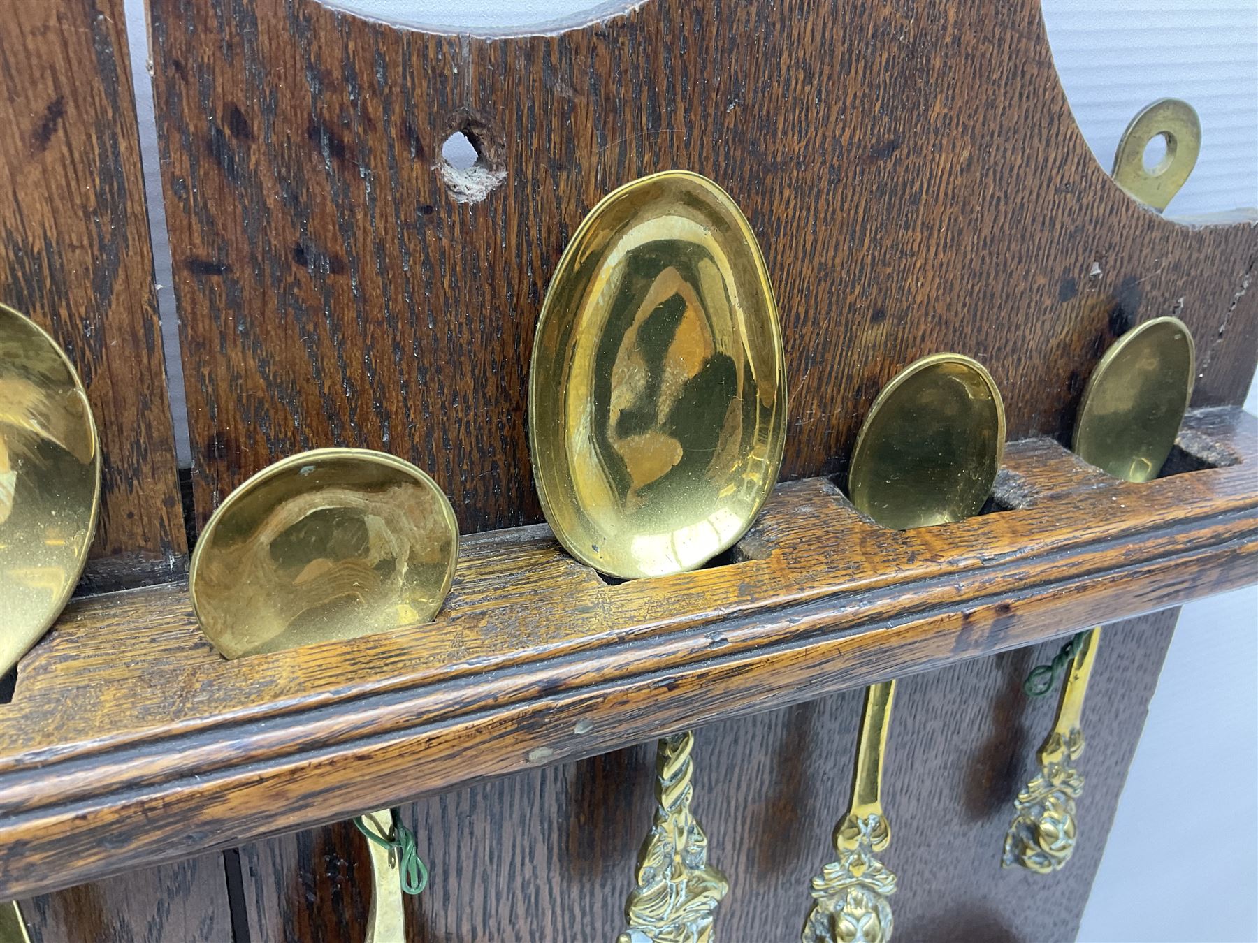 George III oak spoon rack and candle box, the rectangular backplate with shaped  pediment and two six aperture spoon racks, above a candlebox with hinged cover, with various brass spoons and a pair of brass candle snuffers, H56.5cm, W35cm, D14cm 