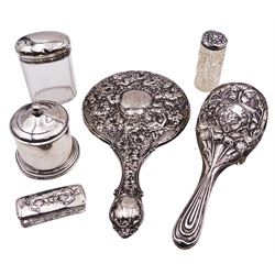 Group of silver, comprising Edwardian silver mounted hand held mirror, embossed throughout with fruiting vines, hallmarked W G Keight & Co, Birmingham 1907, an Edwardian silver mounted hair brush embossed with flowers and vines, hallmarked William Neale & Son, Birmingham 1905, three early 20th century cut glass dressing table jars with silver covers, various hallmarks, and an early 20th century jar and cover of plain cylindrical form with domed cover and ball finial, upon circular stepped base
