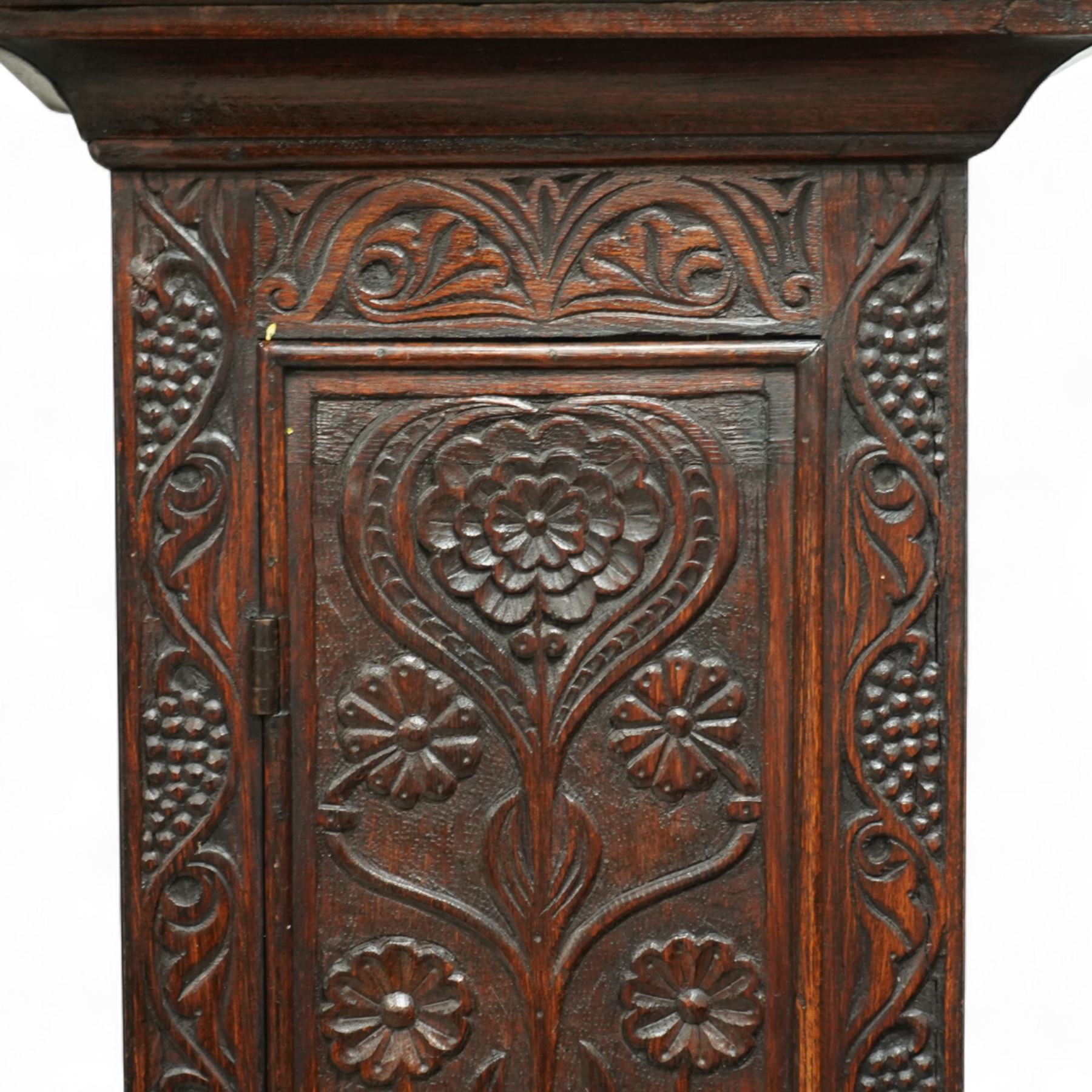 Man Beckett (I) of Stockton on Tees (Co Durham) - 8-day early 18th  century longcase clock in a  profusely carved oak case, with a caddy top, turned finials and attached barley twist pilasters to the break arch hood door, long trunk with carving and a conforming long rectangular door carved with a Celtic depiction of the tree of life, corresponding plinth with a carved and decorative base, break arch brass dial with a rounded brass surround, cast spandrels and silvered boss with the makers name to the arch, matted dial centre with seconds dial, ringed winding apertures, square date aperture and fettled steel hands, silvered chapter with Roman numerals, five minute Arabic's, half hour markers, minute and inner quarter hour tracks, dial pinned to a five pillar movement with inside countwheel striking and a recoil anchor escapement, striking the hours on a bell. With weights and pendulum.
Man Beckett (I), (first name is a biblical name short for Manasseh), was the first member of the Beckett family of prodigious clockmakers working in the North-East of England from 1720 until 1884.