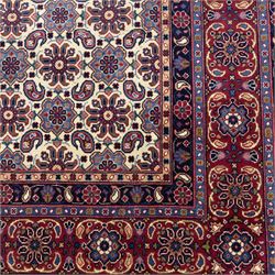 North West Persian Tabriz hand-knotted carpet, ivory field densely decorated with an all-over Herati style (Mahi) lattice composed of stylized rosettes and scrolling leaves, enclosed by a broad madder-red border of palmette and floral vine design, between navy guard stripes, cotton fringe ends 