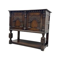 Jacobean design carved oak two door cupboard, the frieze and twin cupboard doors carved with arcaded panels and stylised foliage, raised on baluster supports united by an undertier